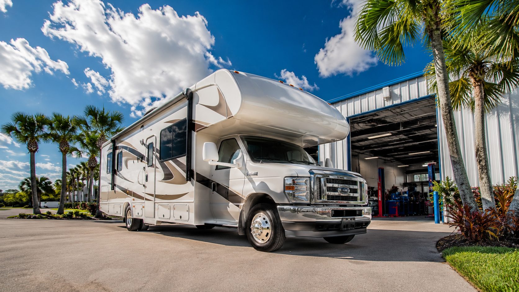Modern Class C motorhome outside a Florida RV repair shop on a bright sunny day